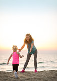 Mother and baby girl having fun time on beach in the evening