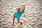 Happy fitness young woman on beach showing thumbs up