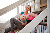 Healthy mother and baby girl sitting on stairs of beach house