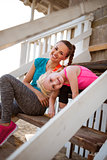Healthy mother and baby girl sitting on stairs of beach house