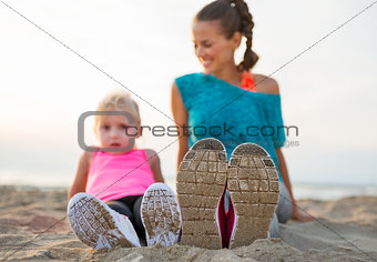 Closeup on legs of fitness mother and baby girl on beach