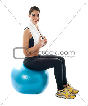 Female fitness trainer sitting on ball