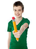 Young boy showing big yellow pencil