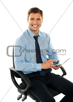 Seated young executive using tablet pc