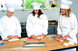 Beautiful female chefs kneading dough