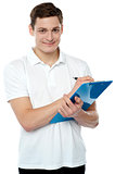 Smiling young man writing on notepad