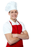 Smiling young chef posing with crossed arms