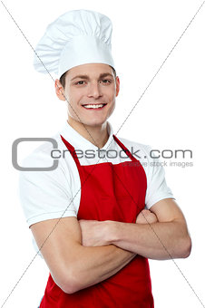 Smiling young chef posing with crossed arms