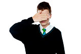 Boy hiding his face and eyes with hand