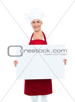 Happy female chef displaying white billboard