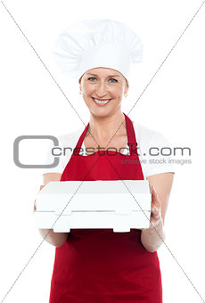 Female baker presenting pizza to you in a box