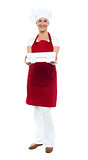 Full length portrait of woman chef offering pizza