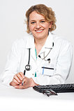 Confident female surgeon sitting idle, holding pen