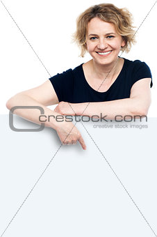 Smiling female pointing at blank whiteboard