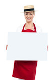 Portrait of female chef in hat with blank ad board