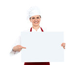 Female chef pointing towards blank whiteboard