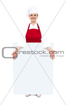 Female cook showing white blank ad board