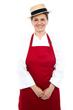 Smiling middle aged female chef wearing hat