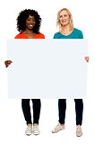 Two young women holding blank billboard