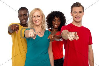 Team of smiling teenagers indicating at you