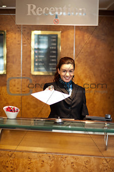 Female receptionist handing over check-out papers