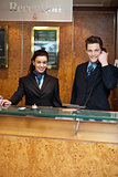 Male and female at hotel reception busy working