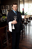 Man posing with a bottle of wine in restaurant