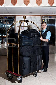Bell boy pushing cart loaded with luggage