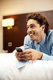 Man holding cellphone and lying on bed, relaxed