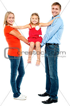 Baby girl sitting on outstretched arms of her parents