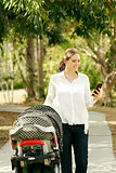 Mother With Baby In Pushchair Sending Message On Phone