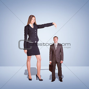 Smiling Young Businesswoman Pointing to small Businessman.