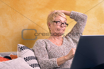 Thoughtful Woman Sitting at Sofa with Laptop