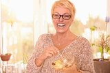 Vivacious middle-aged woman eating fruit salad