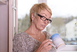 Serious Blond Woman with Glasses Holding a Cup