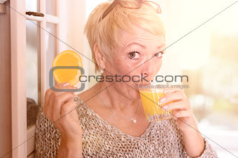 Woman Drinking Juice and Holding Orange Slice