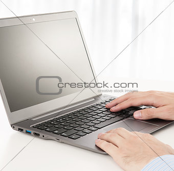 Rear view of business man hands busy using laptop at office desk