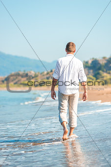 successful young man walking along a sandy beach