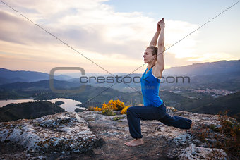 Young Caucasian woman working out on a rock against valley view
