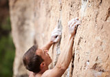 Cropped view of male rock climber on cliff, hands in focus