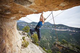 Young female rock climber struggling to make the next movement up