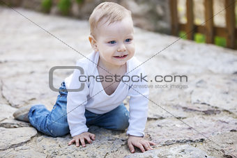 Cute little boy crawling on stone paved sidewalk