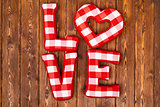 Love word of plush red letters on wood background. Full plaid textile