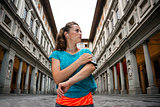 Fitness woman using cell phone near uffizi gallery in florence, 