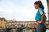 Thoughtful fitness woman standing in front of ponte vecchio in f