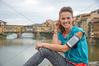 Portrait of happy fitness woman in earphones in front of ponte v