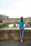 Fitness woman looking on ponte vecchio in florence, italy. rear 