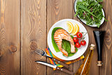 Grilled salmon, salad and condiments on wooden table