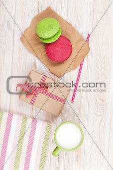 Colorful macarons, cup of milk and gift box