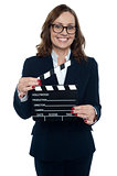 Gorgeous corporate woman holding a clapperboard